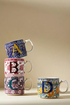 three colorful coffee mugs stacked on top of each other with the letter b in them