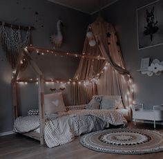 a bedroom with lights strung from the ceiling and curtains on the bed, along with a round rug