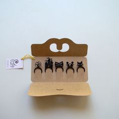 an open cardboard box with five small black cats on it and a tag hanging from the front