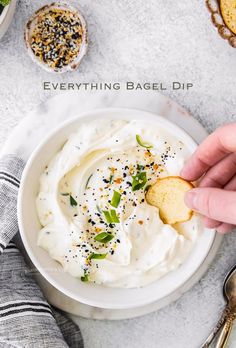 a hand dipping a cracker into a bowl of hummus