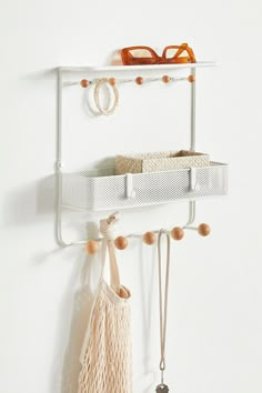 a pair of glasses hanging on a white wall next to a shelf with hooks and tassels