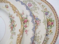 four plates with floral designs on them sitting next to each other in a row and one is empty