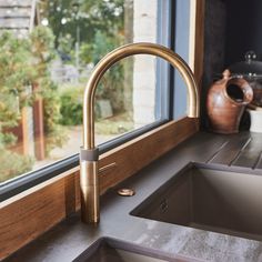 a kitchen sink with a faucet next to it and a window in the background