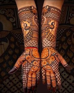 two hands with henna designs on them, one is painted orange and the other is brown