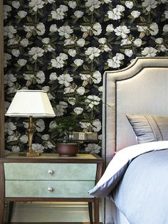 a bedroom with floral wallpaper and an old fashioned night stand next to the bed