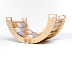 a wooden rocking chair with pillows on the back and sides, in front of a white background