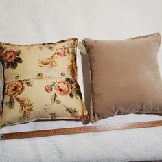 two pillows sitting next to each other on top of a bed with a ruler in front of them