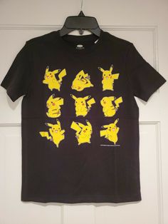 a black t - shirt with yellow pokemon images on the front and back, hanging from a hanger