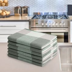 a stack of folded towels sitting on top of a kitchen counter next to a stove