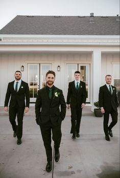 a group of men in suits and ties walking down a sidewalk next to a house