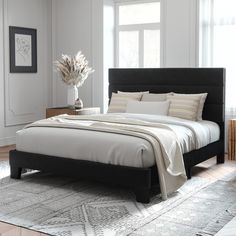 a bedroom with a bed, nightstands and rug on the floor in front of two windows