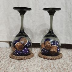 two wine glasses with corks in them sitting on the floor next to each other