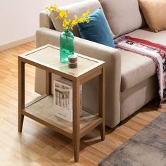 a living room with a couch, coffee table and flowers on the end table in front of it