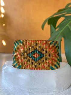 a beaded bracelet sitting on top of a white table next to a potted plant