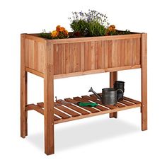 a wooden planter with flowers and gardening tools on it's side shelf, against a white background