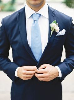 a man wearing a blue suit and tie with a flower in his lapel pocket