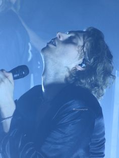 a man singing into a microphone on stage