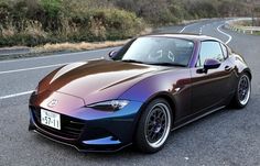 a purple and blue sports car parked on the side of the road