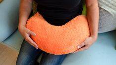 a woman holding an orange heart shaped pillow