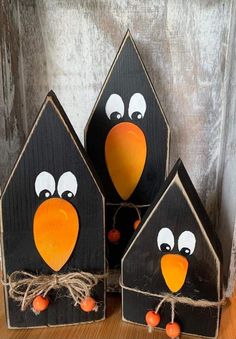 three black and orange bird houses with eyes painted on the front, one has an orange beak