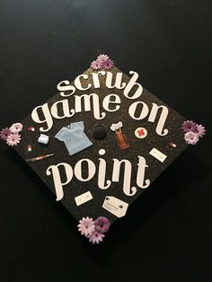 a graduation cap that says scrub game on point with flowers and other items around it