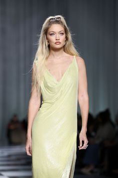 a model walks down the runway in a yellow dress