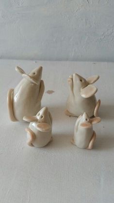 three ceramic figurines of mice sitting next to each other on a white surface