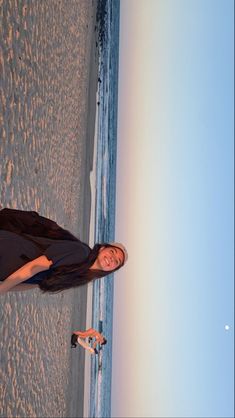 a woman standing on top of a beach next to the ocean