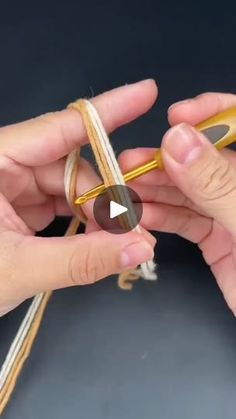 two hands are holding scissors and stringing the ends of some yarns with one hand