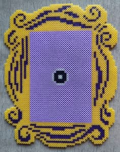 a yellow and purple frame with a black square in the center on a gray surface