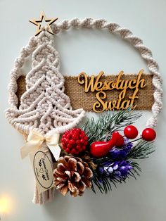 a christmas wreath hanging on the wall with pine cones, berries and other holiday decorations