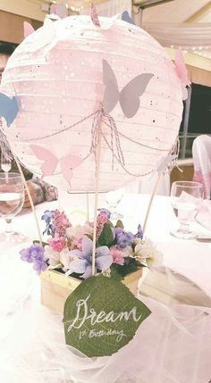 an umbrella centerpiece with flowers and butterflies on it at a wedding or baby shower