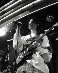 a man holding a guitar while standing in front of a microphone