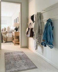 a living room filled with furniture and lots of coats hanging on the wall next to a rug