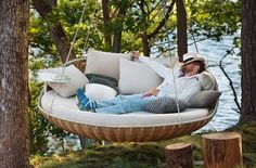 a man laying in a hanging chair next to some trees