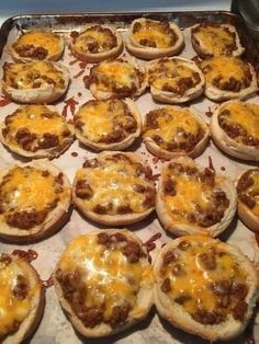 many small pizzas are sitting on a baking sheet and ready to be baked in the oven