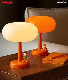 an orange lamp sitting on top of a table next to a book and pen holder