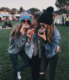 three girls are posing for the camera with doughnuts in front of their faces