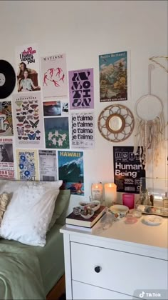 a bed room with a neatly made bed and lots of posters on the wall above it