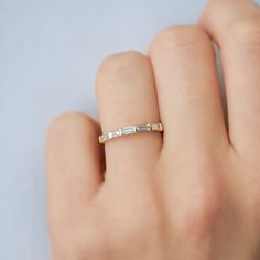 a woman's hand wearing a gold ring with three baguettes on it