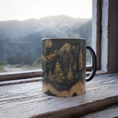 a coffee mug sitting on top of a wooden window sill next to a window