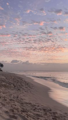 the sun is setting at the beach and people are out in the water