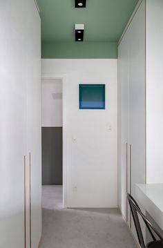 an empty hallway with white walls and green ceiling