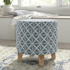 a blue and white ottoman sitting on top of a rug in front of a window