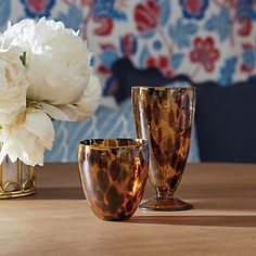 three vases sitting on top of a wooden table next to a white flower arrangement