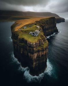 an island with two houses on it in the middle of the ocean under a cloudy sky