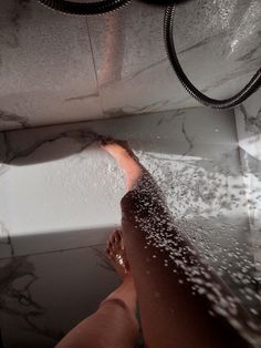 a person standing in a bathtub with water coming from the faucet