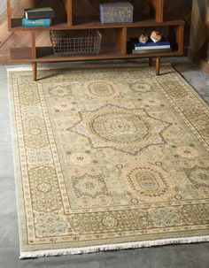 a large rug with an ornate design on the floor in front of a book shelf