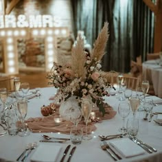 a table set with silverware, wine glasses and flower centerpieces for a wedding reception