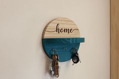 a wooden sign that says home hanging on a wall with key hooks and keys in front of it